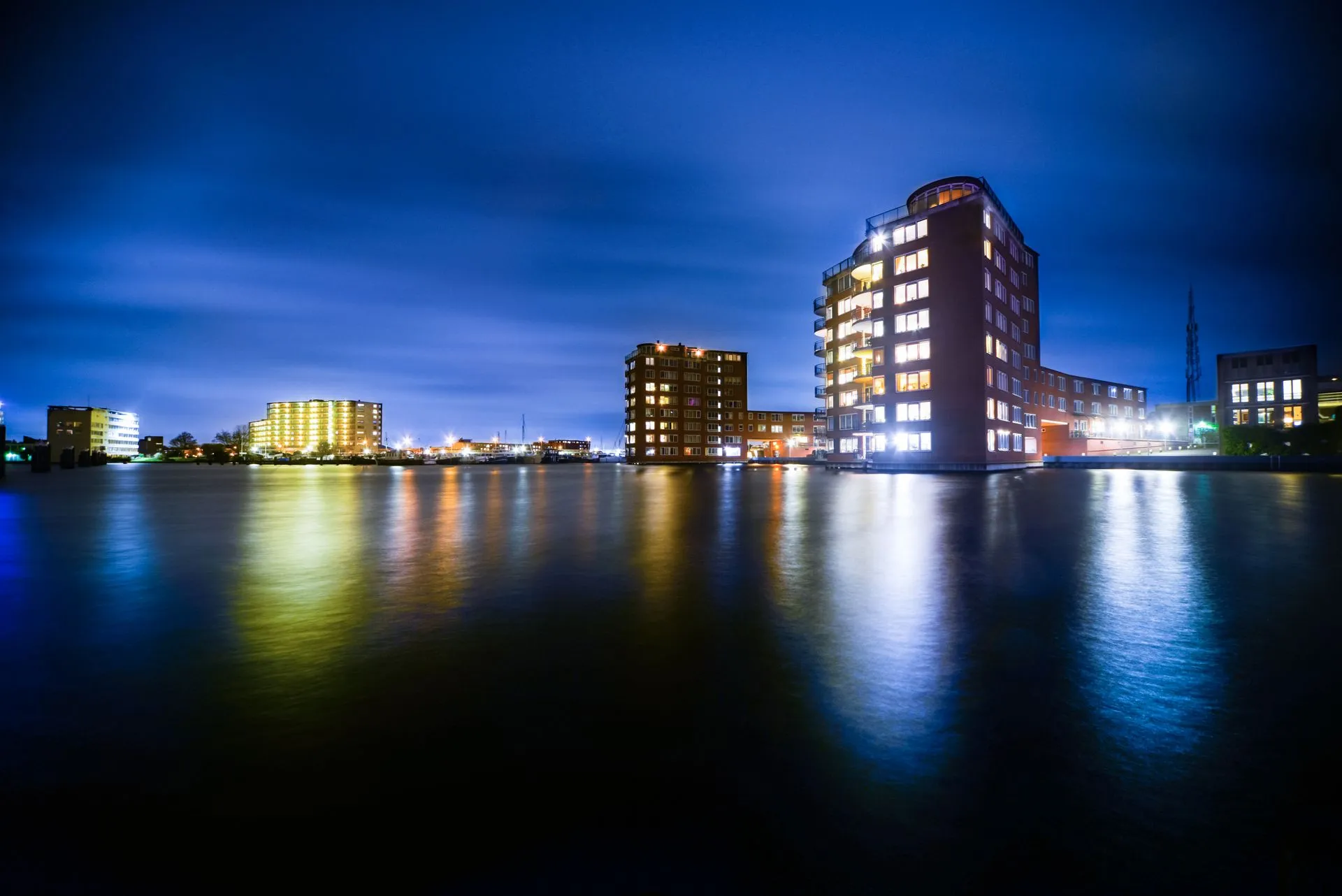 Blue-hour view of waterfront buildings reflected on calm water