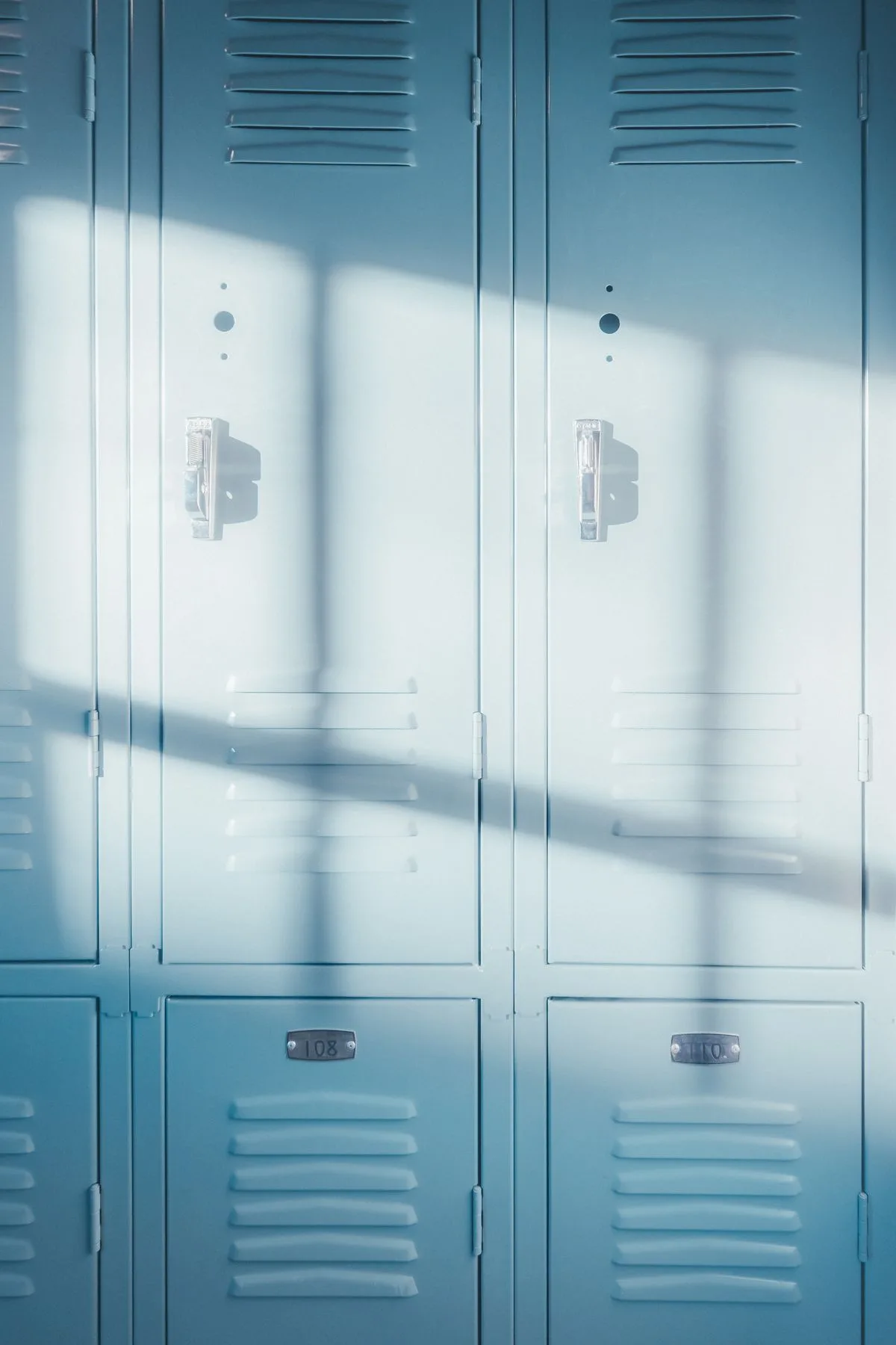 Sunlit pale-blue school lockers in a corridor — hallway deployment space