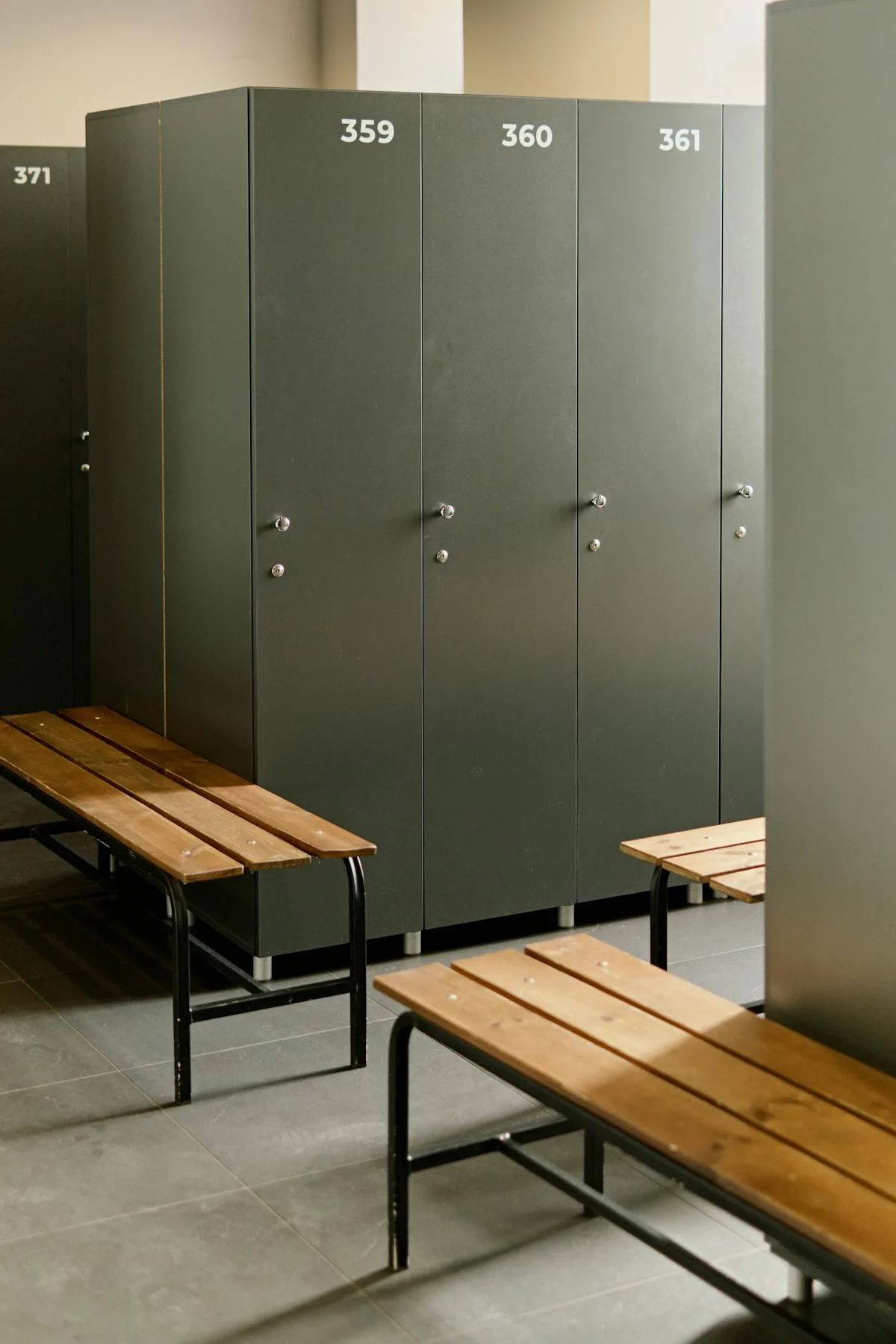 Empty locker room with grey lockers and wooden benches — locker room deployment space