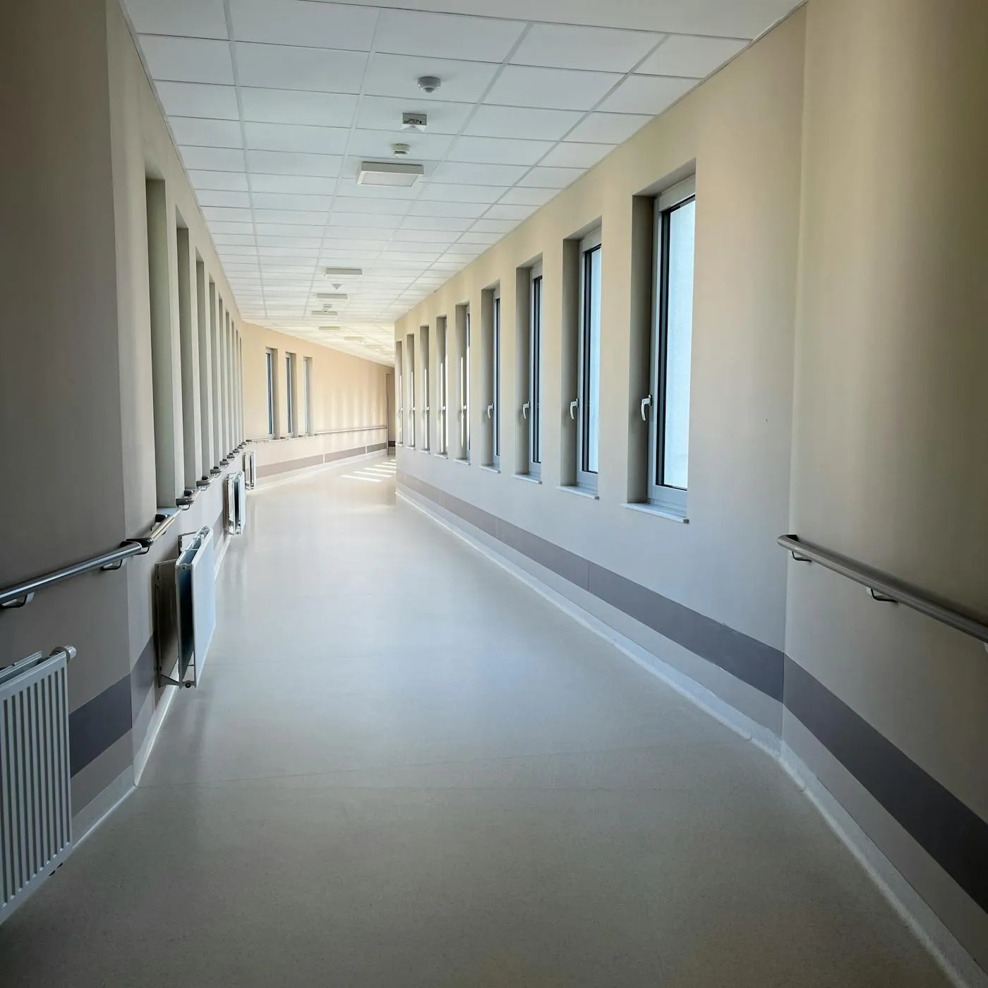 Bright modern hospital corridor with handrails and tall windows